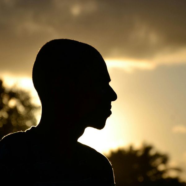 Silhouette of a person meditating against a warm, abstract background.